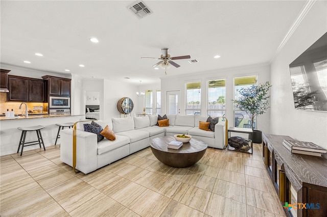 living room with sink, ceiling fan with notable chandelier, and crown molding