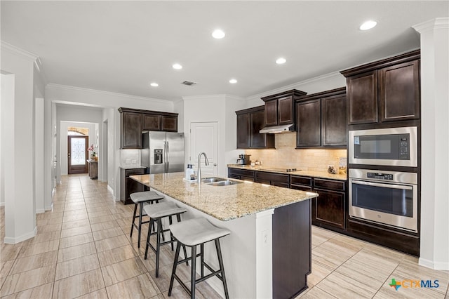 kitchen featuring light stone counters, crown molding, appliances with stainless steel finishes, sink, and a kitchen island with sink