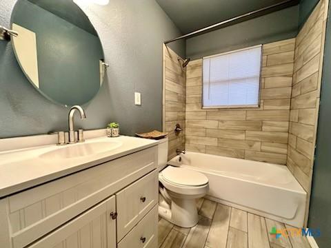 full bathroom with toilet, vanity, and tiled shower / bath combo