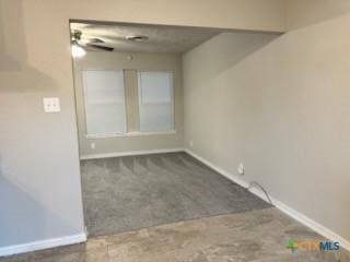 spare room featuring ceiling fan and dark carpet