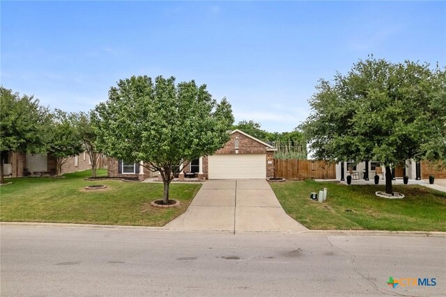 obstructed view of property with driveway, a garage, brick siding, fence, and a front lawn