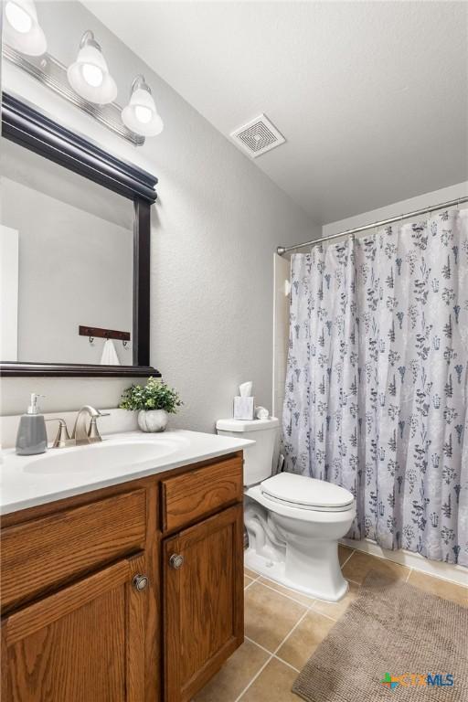 full bathroom featuring toilet, tile patterned floors, visible vents, and vanity