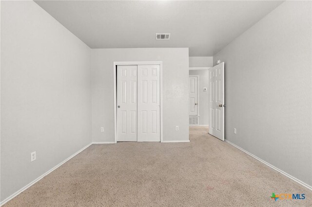 unfurnished bedroom with visible vents, baseboards, carpet floors, and a closet