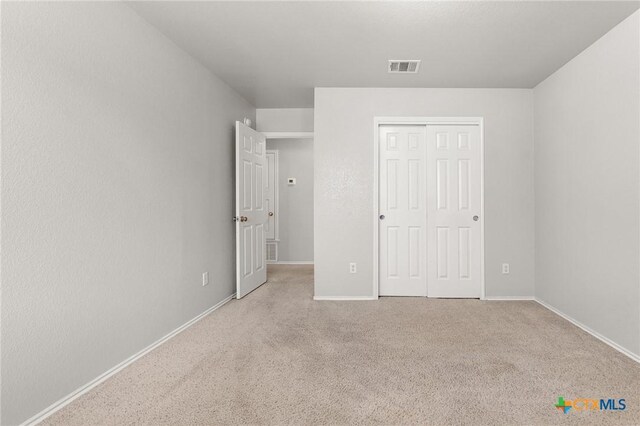 unfurnished bedroom featuring baseboards, carpet, a closet, and visible vents