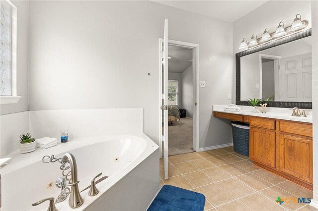 ensuite bathroom with tile patterned flooring, vanity, a jetted tub, baseboards, and connected bathroom