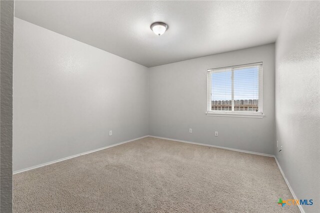 empty room with baseboards and carpet