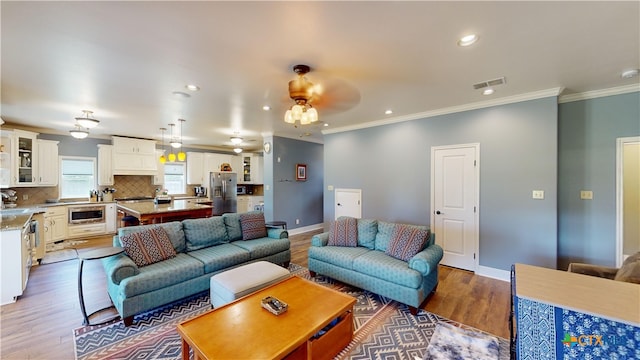 living room with ceiling fan, wood-type flooring, and crown molding