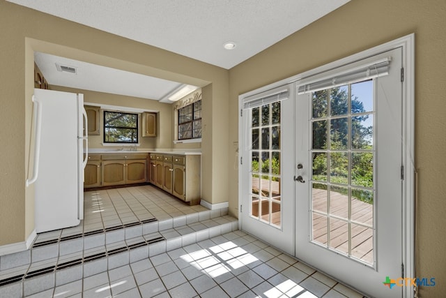 doorway to outside featuring light tile patterned floors, french doors, and a textured ceiling