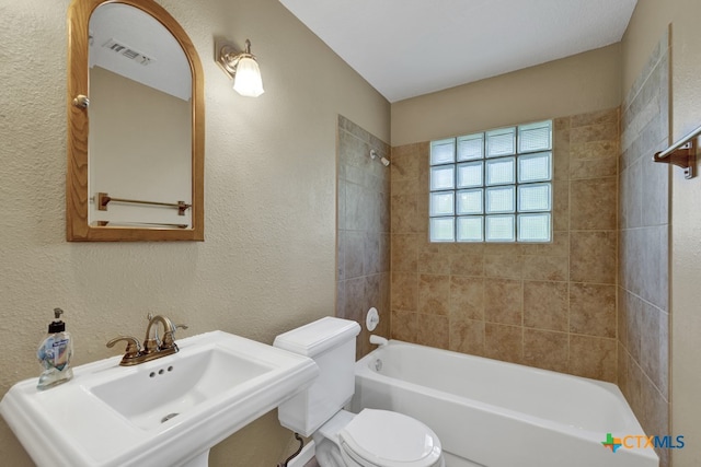 full bathroom with sink, tiled shower / bath combo, and toilet