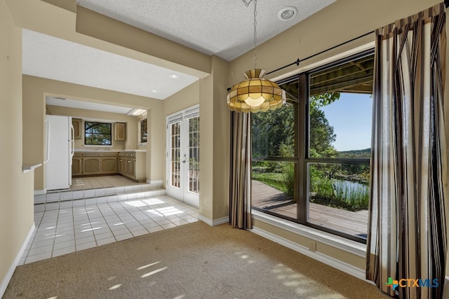 unfurnished dining area with french doors, a water view, a textured ceiling, and light tile patterned floors