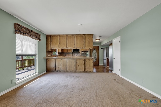 kitchen with tasteful backsplash, appliances with stainless steel finishes, kitchen peninsula, and carpet floors