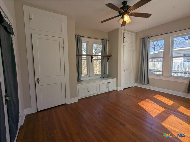 207 W 5th St, Lampasas, TX 76550 - unfurnished bedroom featuring dark wood finished floors, multiple windows, and a ceiling fan