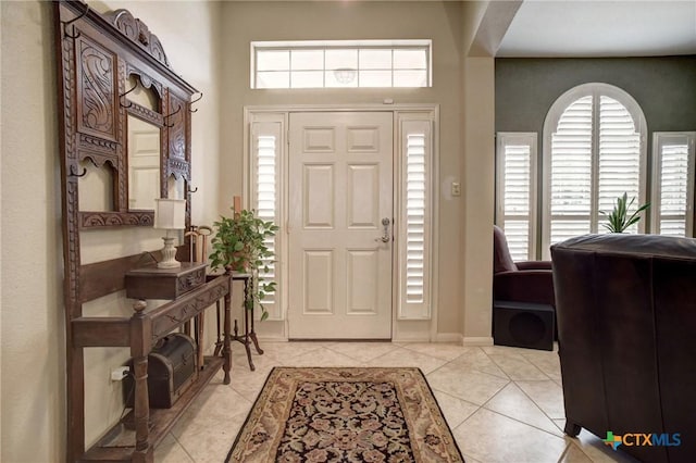 entrance foyer with a healthy amount of sunlight, baseboards, and light tile patterned flooring