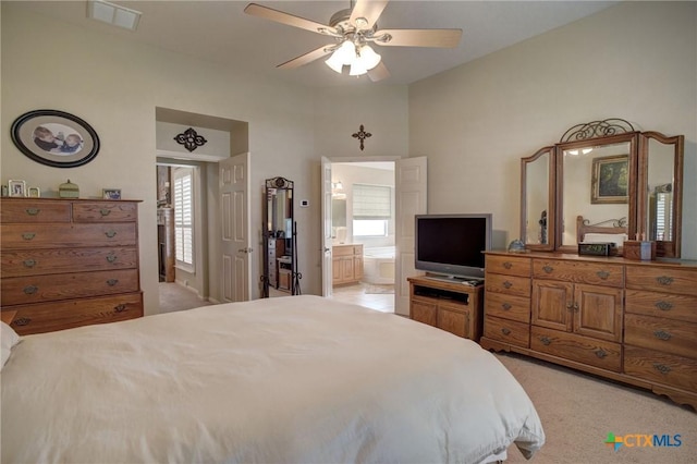 bedroom with a ceiling fan, visible vents, connected bathroom, and light carpet