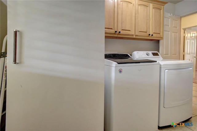 laundry room featuring light tile patterned floors, washer and clothes dryer, and cabinet space