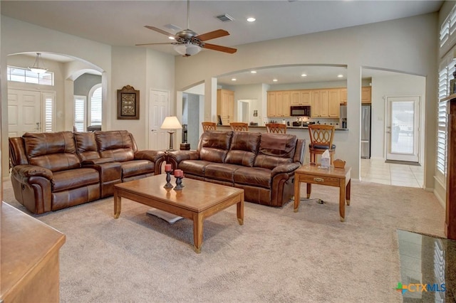 living area with arched walkways, light tile patterned floors, recessed lighting, visible vents, and light carpet