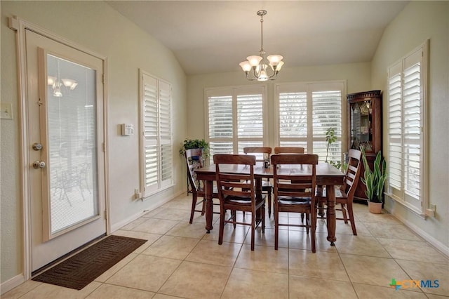 dining space with a chandelier, light tile patterned floors, lofted ceiling, and baseboards