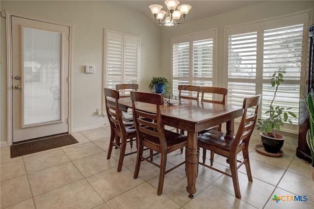 dining room featuring a healthy amount of sunlight, an inviting chandelier, vaulted ceiling, and light tile patterned flooring