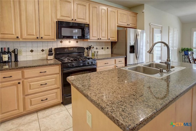 kitchen with black appliances, stone counters, a sink, and a kitchen island with sink