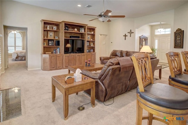 living room featuring light carpet, plenty of natural light, visible vents, and arched walkways