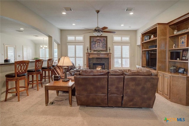 living room with light colored carpet, a wealth of natural light, visible vents, and a tiled fireplace