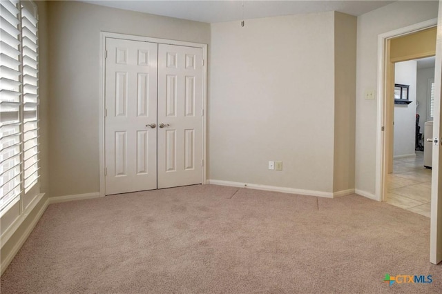 unfurnished bedroom with baseboards, a closet, and light colored carpet