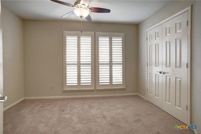 spare room featuring ceiling fan, baseboards, and light colored carpet