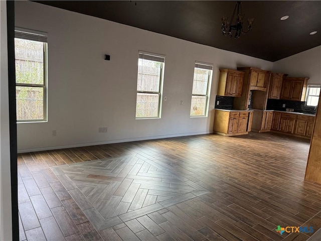 unfurnished living room with a chandelier, vaulted ceiling, and wood-type flooring