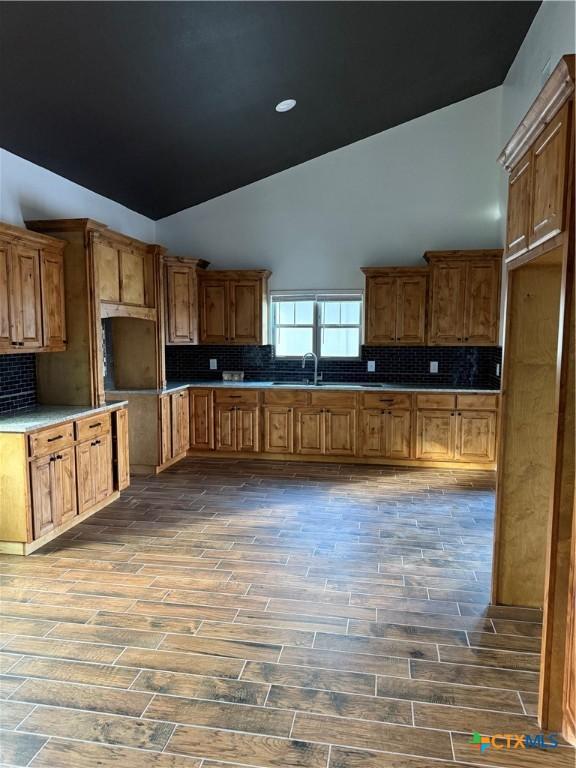 kitchen featuring dark hardwood / wood-style floors, sink, high vaulted ceiling, and tasteful backsplash