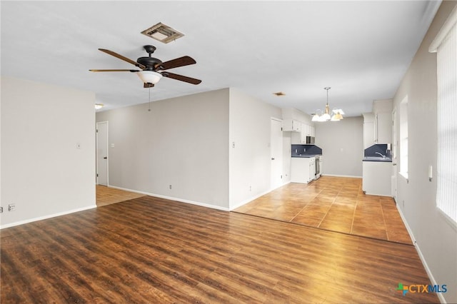 unfurnished living room featuring sink, ceiling fan with notable chandelier, and light hardwood / wood-style floors