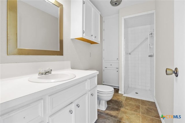 bathroom featuring a tile shower, vanity, and toilet