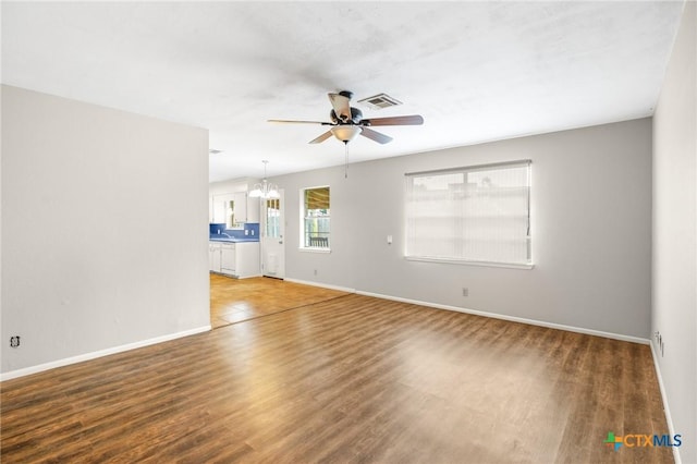 unfurnished living room featuring hardwood / wood-style floors and ceiling fan with notable chandelier