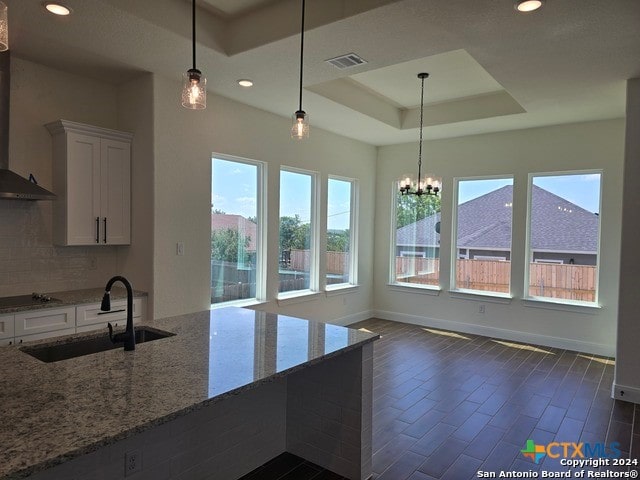 kitchen with white cabinets, light stone countertops, hanging light fixtures, and sink