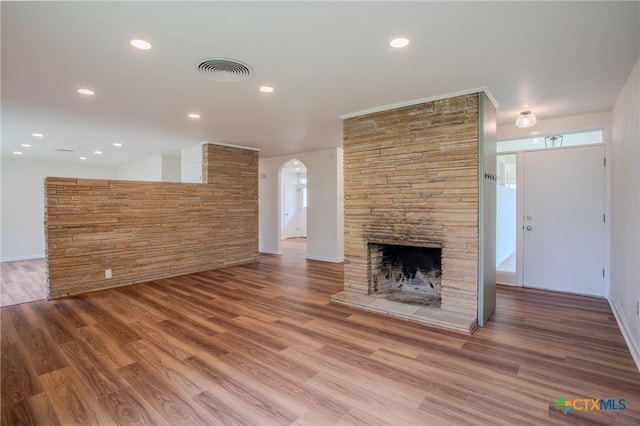 2906 Arroyo Dr, Victoria, TX 77901 - unfurnished living room featuring arched walkways, a stone fireplace, wood finished floors, and recessed lighting