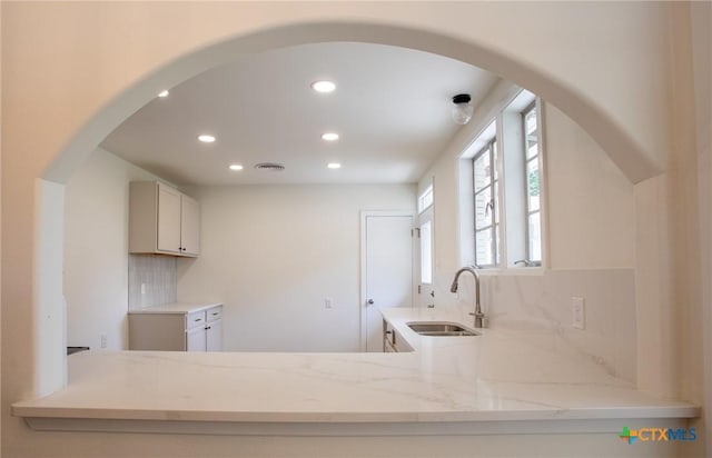 2906 Arroyo Dr, Victoria, TX 77901 - kitchen featuring recessed lighting, light stone counters, tasteful backsplash, arched walkways, and a peninsula