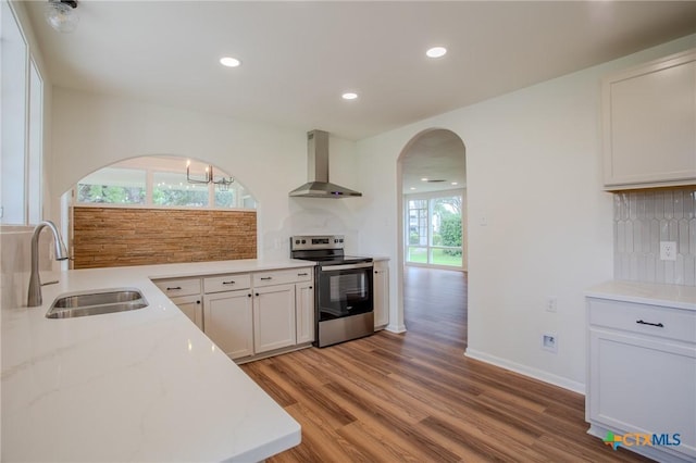 2906 Arroyo Dr, Victoria, TX 77901 - kitchen with wall chimney range hood, stainless steel electric range, arched walkways, backsplash, and recessed lighting