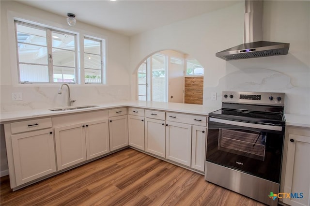 2906 Arroyo Dr, Victoria, TX 77901 - kitchen with stainless steel electric stove, wall chimney exhaust hood, light wood-style floors, and plenty of natural light