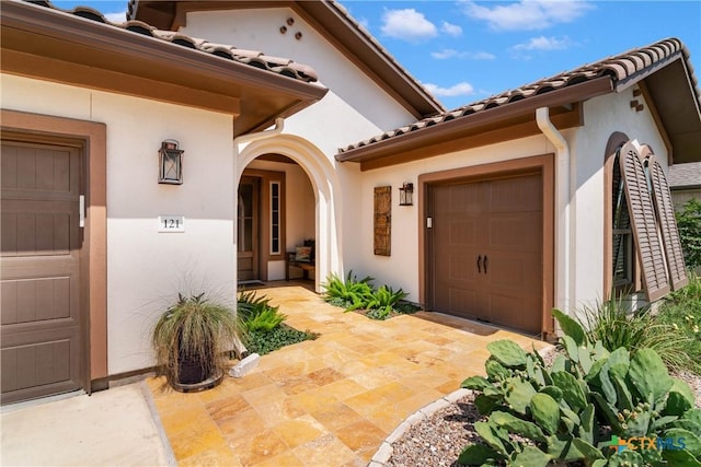 121 Wild Honeysuckle Way, San Marcos, TX 78666 - doorway to property with a garage, stucco siding, and a tile roof