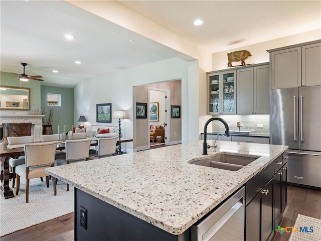121 Wild Honeysuckle Way, San Marcos, TX 78666 - kitchen featuring appliances with stainless steel finishes, a sink, a kitchen island with sink, light stone countertops, and recessed lighting