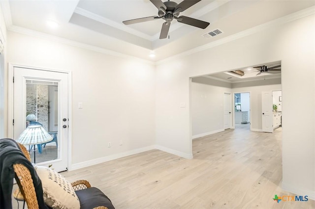 unfurnished room with ceiling fan, visible vents, crown molding, light wood-type flooring, and a tray ceiling