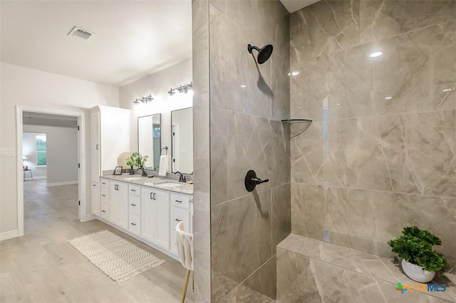 full bathroom featuring double vanity, a walk in shower, visible vents, and a sink