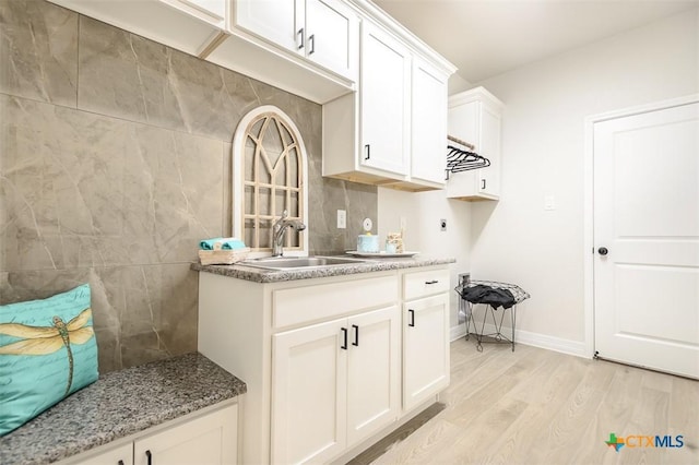 washroom featuring light wood-style floors, baseboards, a sink, cabinet space, and hookup for an electric dryer