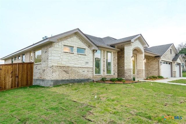 view of front facade featuring fence, a garage, a front lawn, and stone siding