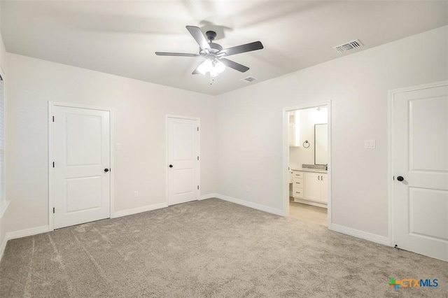 unfurnished bedroom with baseboards, light carpet, connected bathroom, and visible vents