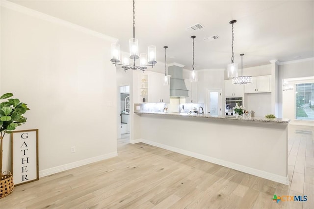 kitchen featuring white cabinets, open shelves, an inviting chandelier, light countertops, and light wood-type flooring