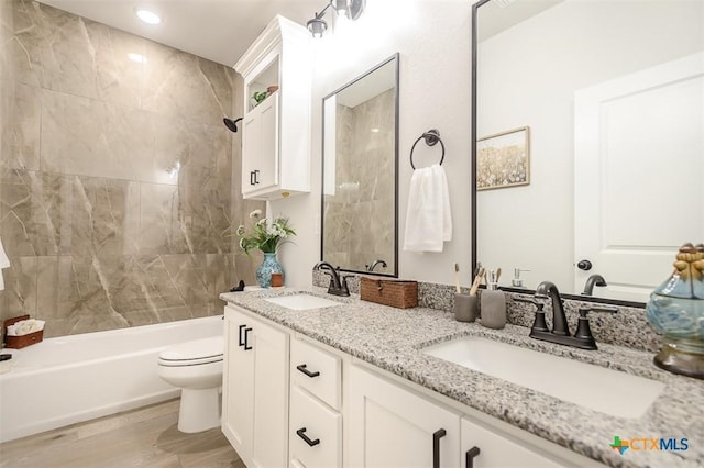 bathroom featuring double vanity, a sink, washtub / shower combination, and wood finished floors