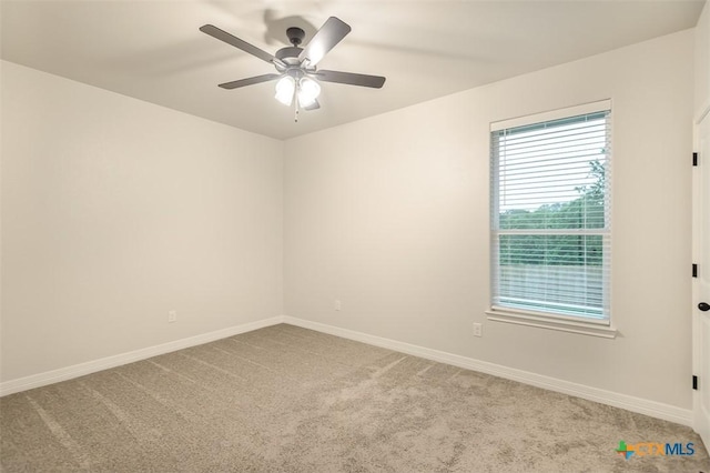 carpeted spare room with a ceiling fan and baseboards