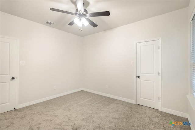 unfurnished room with carpet floors, baseboards, a ceiling fan, and visible vents