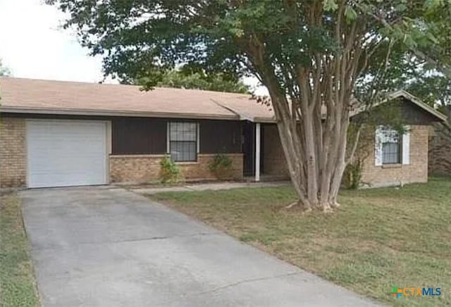 ranch-style home with a garage, brick siding, driveway, and a front lawn