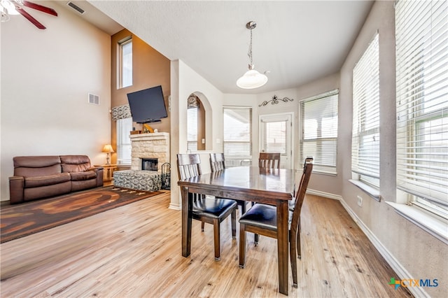 dining room with ceiling fan, a fireplace, and light hardwood / wood-style flooring